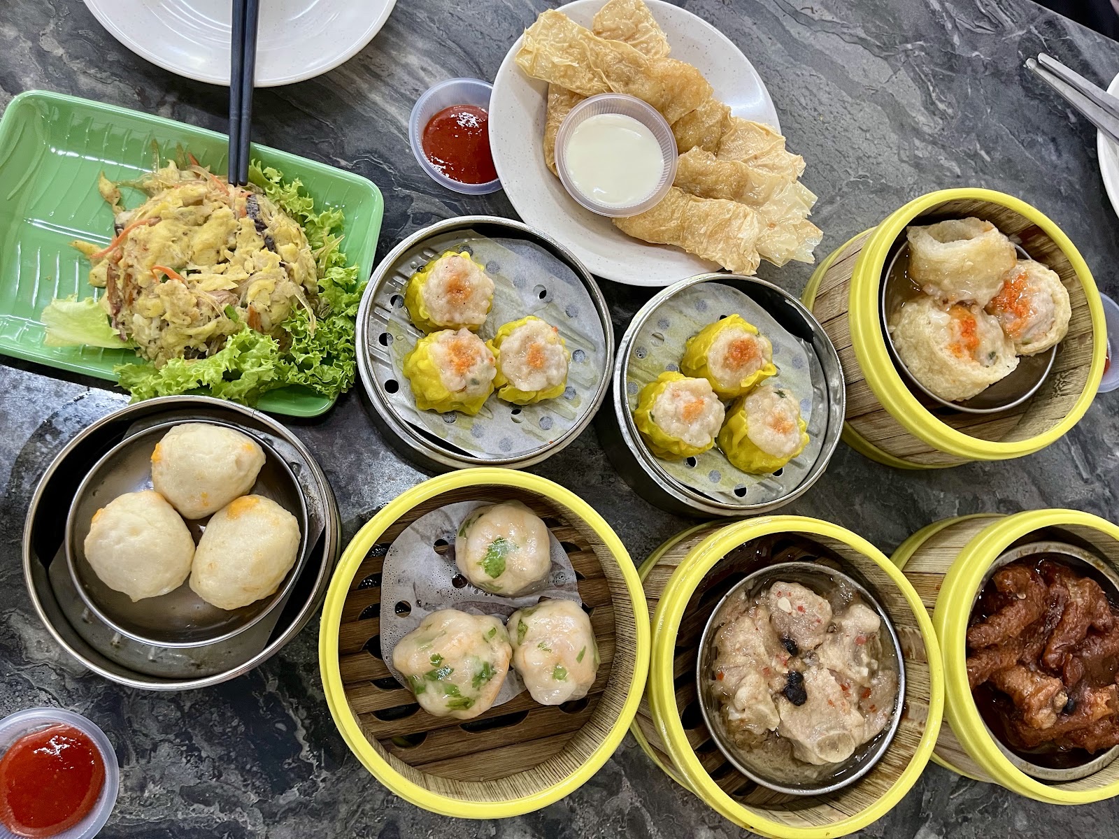 A bird's-eye spread of dim sum baskets at Maxim — har gao, siu mai, char siu bao, custard buns and lo mai gai